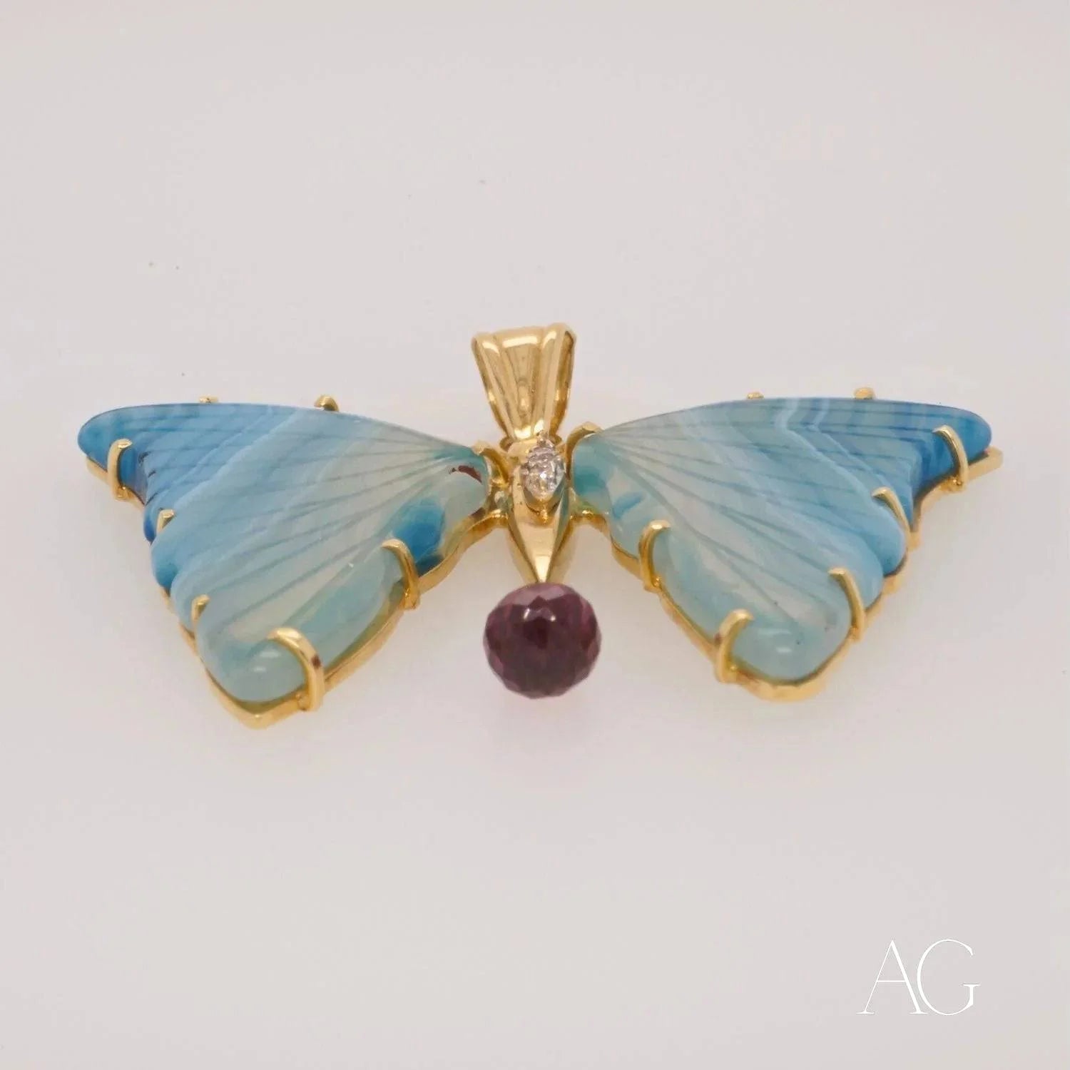 Butterfly pendant with blue wings in 18k yellow gold and purple gemstone drop