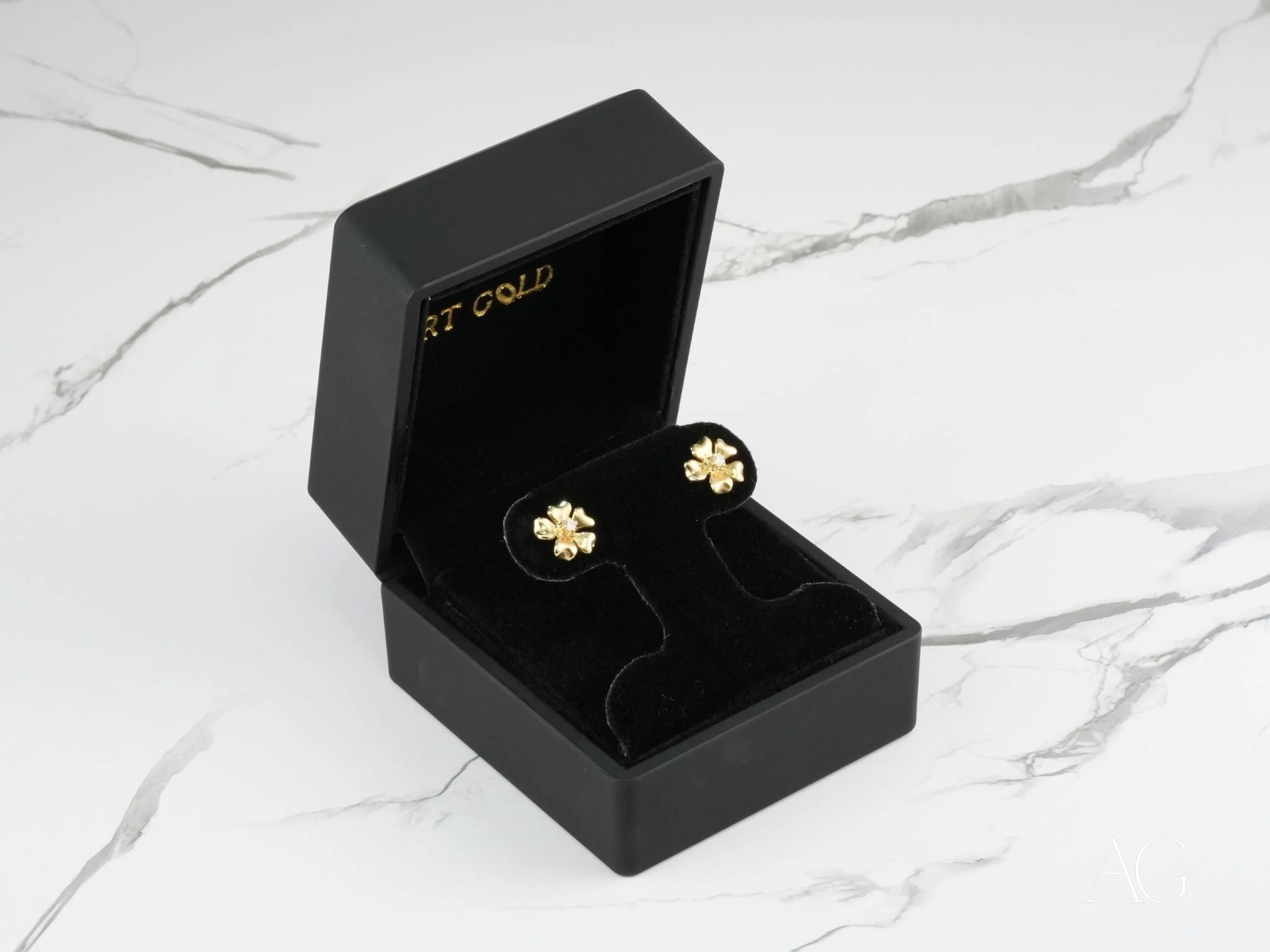 Gold clover earrings in a black jewelry box from Floral Elegance with 0.06ct diamond flower