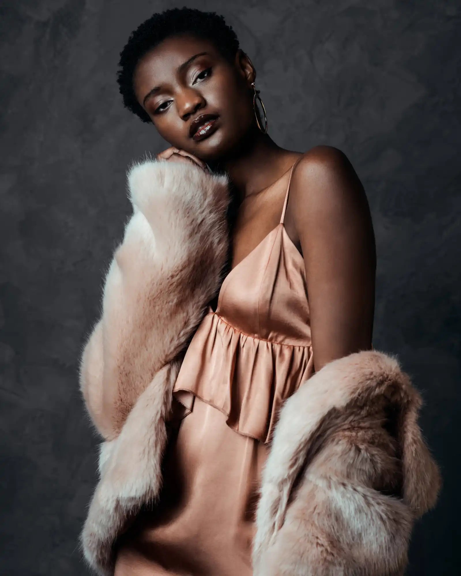 A glamorous fashion portrait featuring a peach silk dress and plush fur coat.