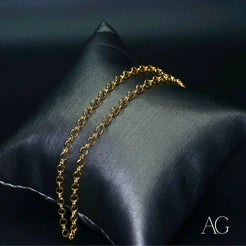 18k gold anklet elegantly draped on dark gray cushion showcasing timeless elegance