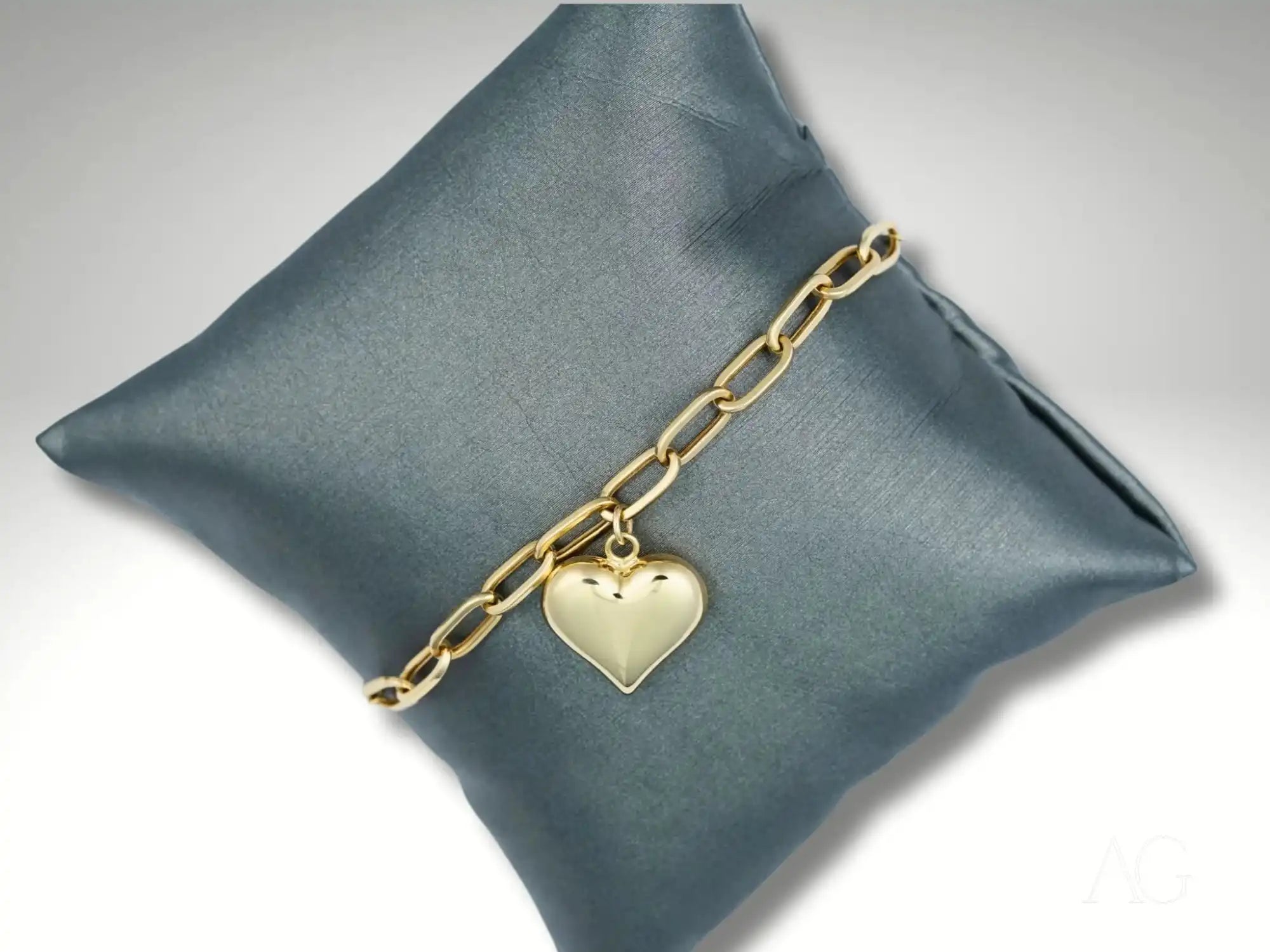 Gold chain bracelet with a heart-shaped charm.