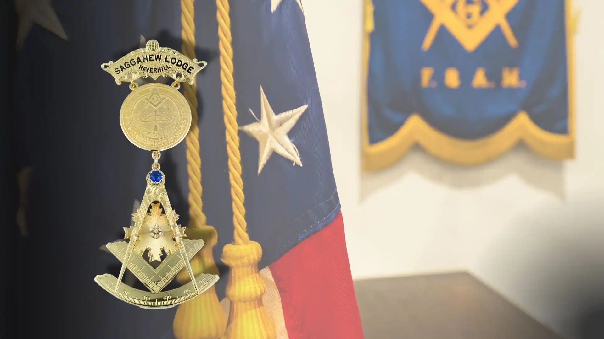 Gold Masonic Past Master jewel with square and compasses symbol hanging from a medal.