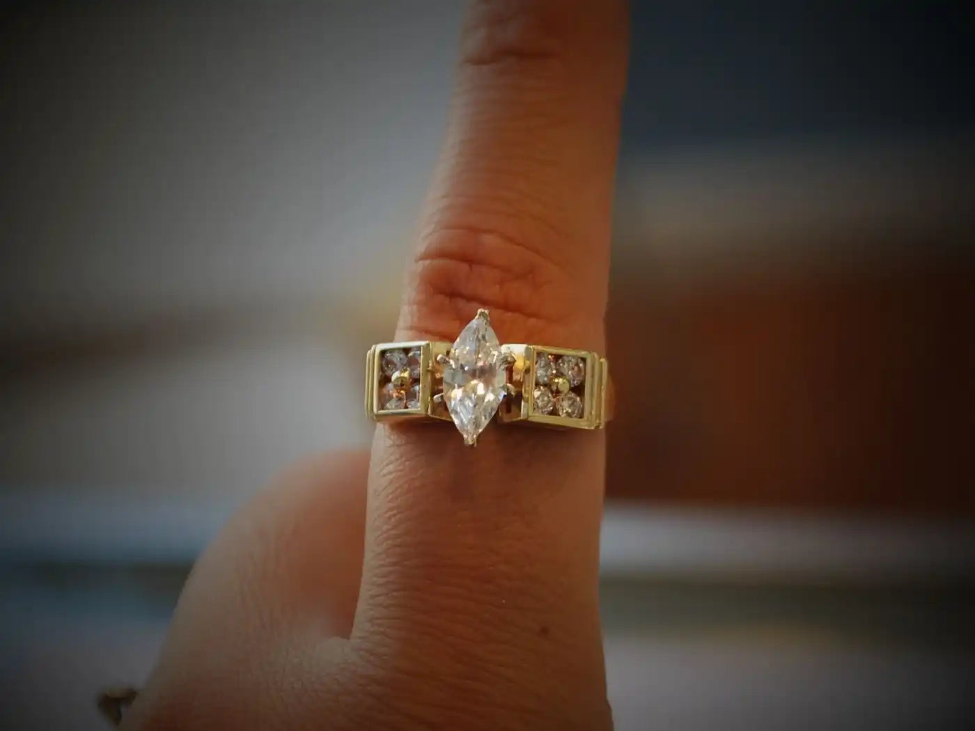 Gold ring featuring a marquise-cut diamond center stone with channel-set accent diamonds.