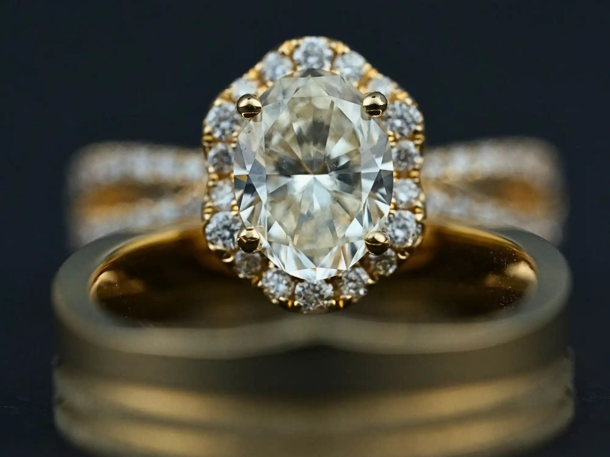 Gold ring featuring an oval-cut center diamond surrounded by smaller diamonds in a halo setting.