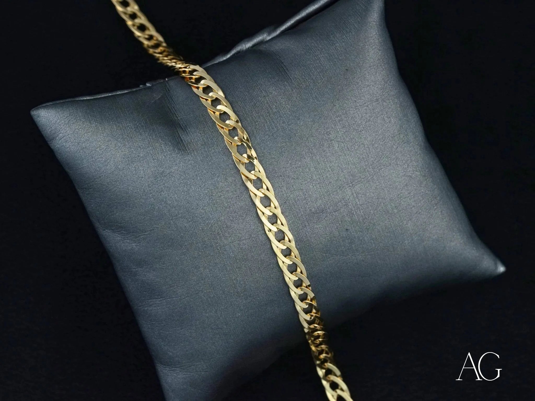 Gold chain necklace on gray cushion showcasing 18k solid gold double flated link design