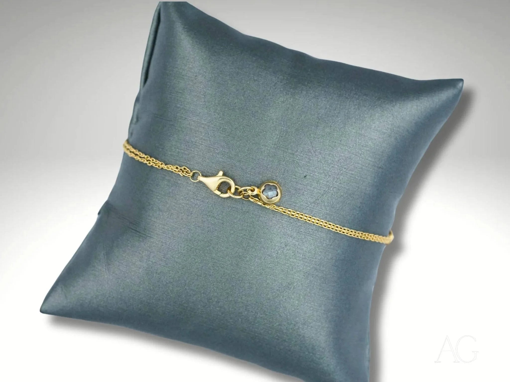 Delicate 18k gold heart motif bracelet showcased on a gray cushion