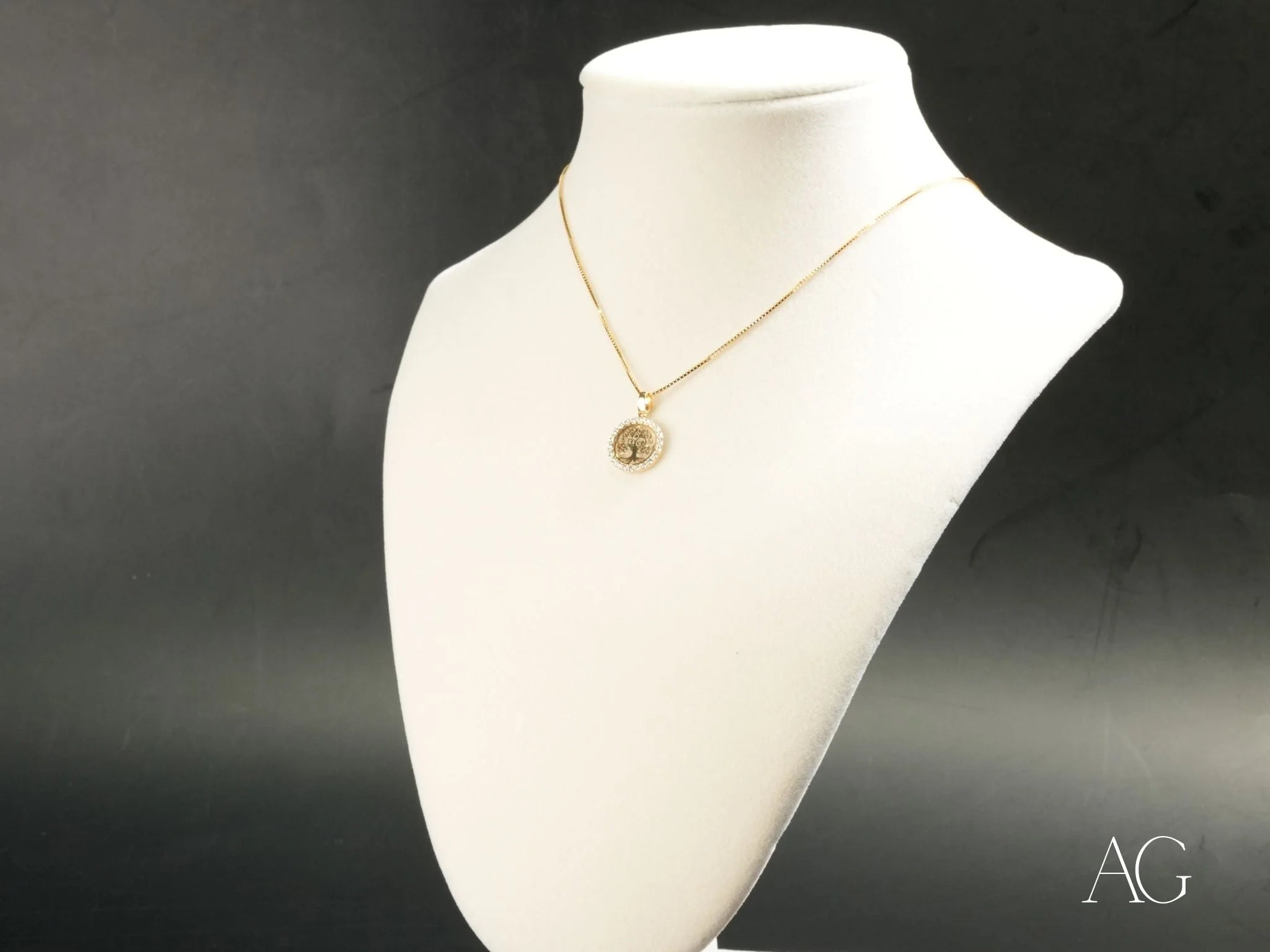 Gold-toned Árvore da Vida pendant on a white jewelry bust, showcasing 18k gold elegance