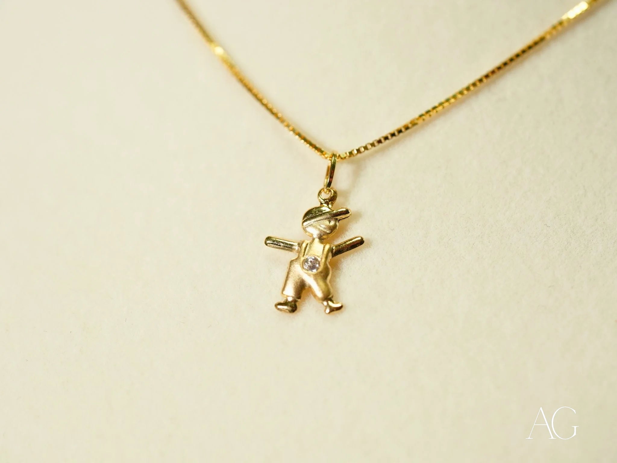 Gold pendant necklace with a golden mini charm of a cherub symbolizing innocence and love