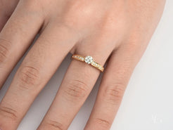 Gold engagement ring featuring a central diamond on finger, showcasing Golden Promise design