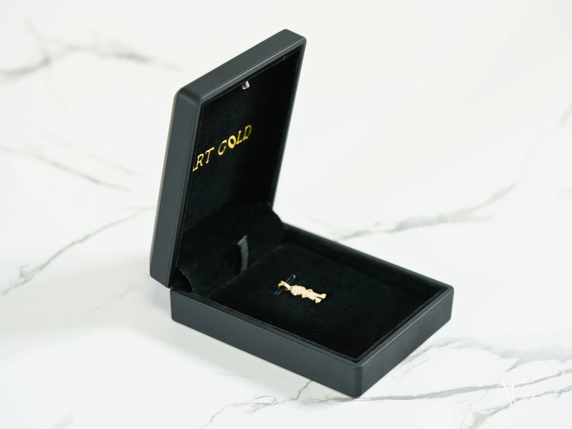 Black jewelry box with Golden Play 18k Gold pendant and brooch inside