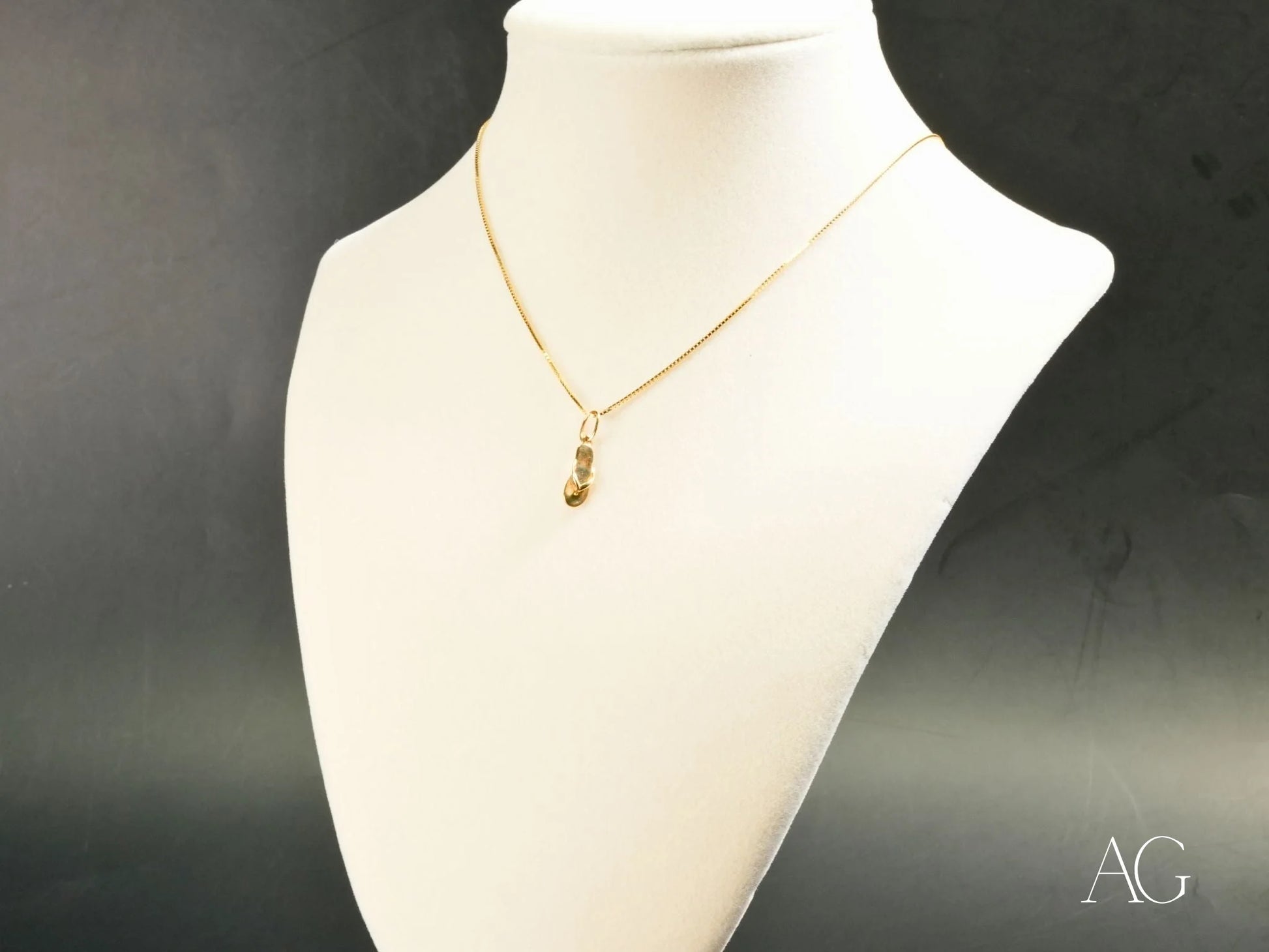 Gold-toned necklace with a Golden Flip Flop pendant on a white jewelry bust