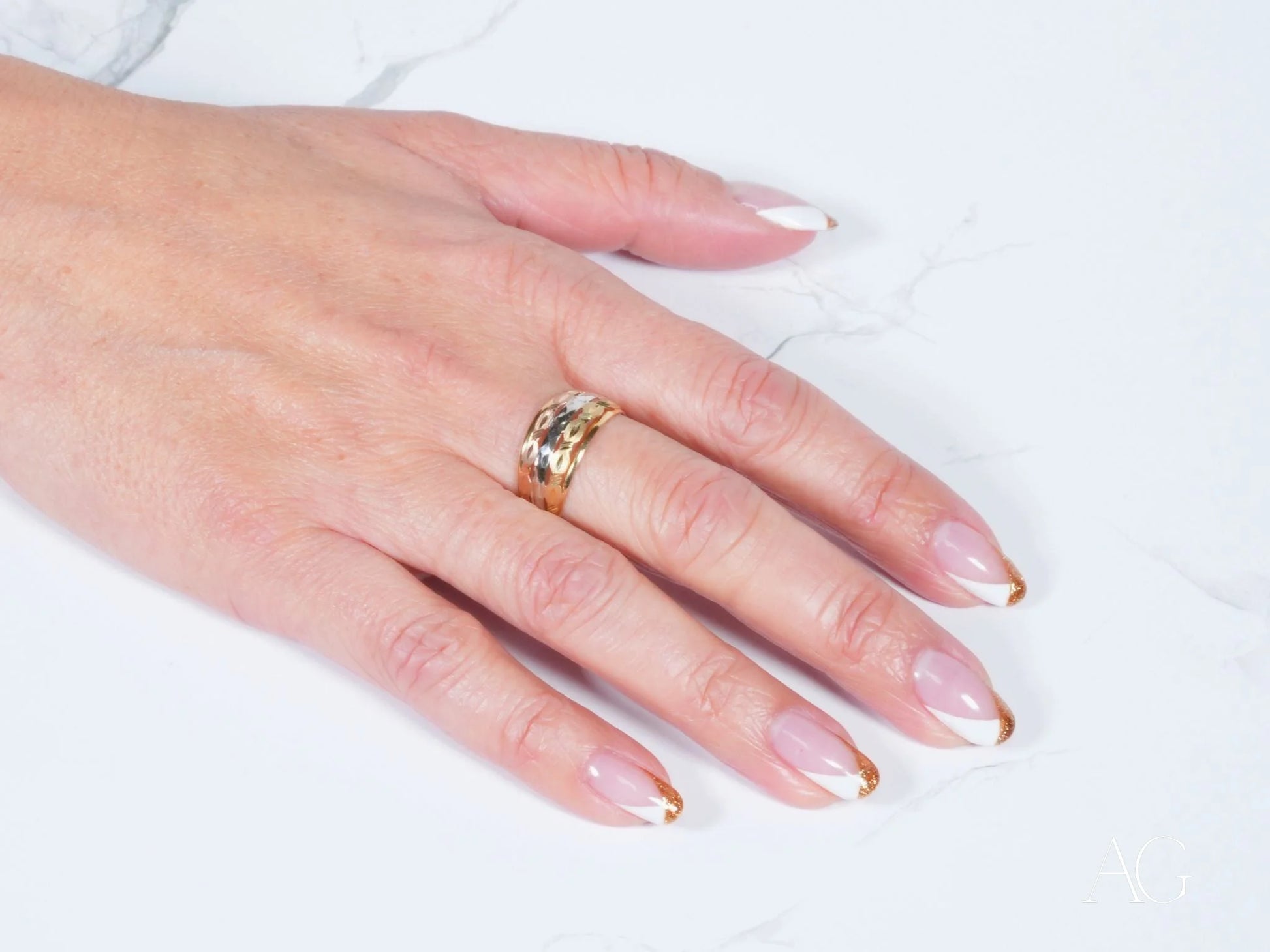 Gold ring with decorative design on manicured hand showcasing Golden Spectrum 18k gold jewelry