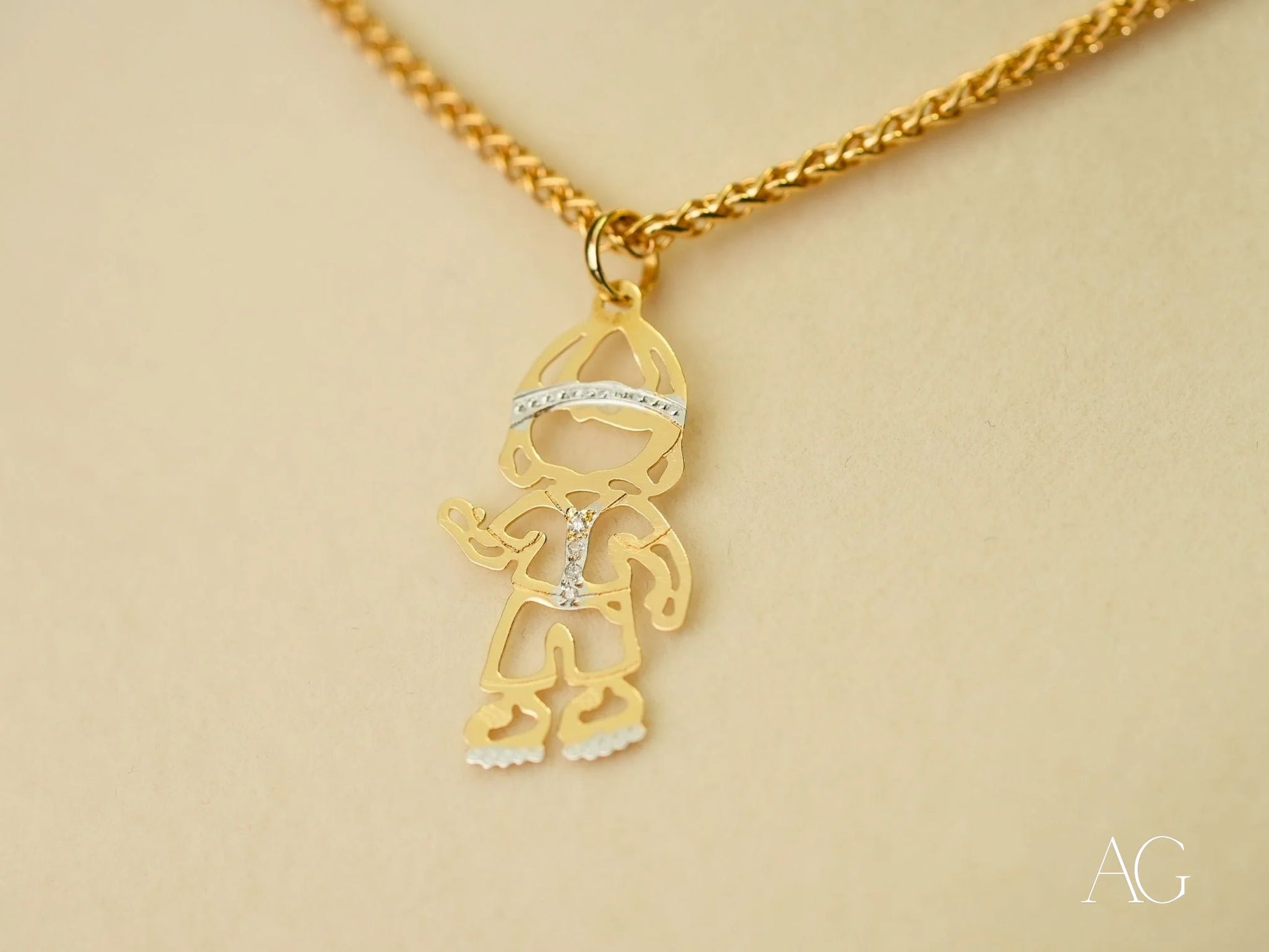 Gold pendant necklace with a stylized boy figure and diamond accents in 18k gold