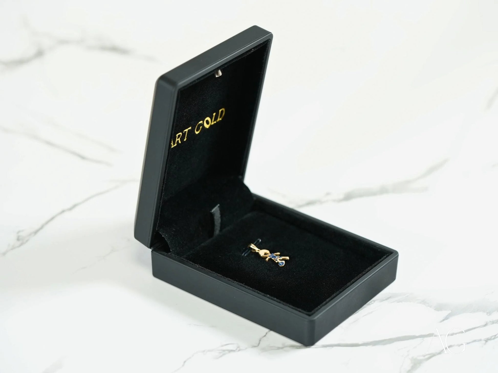 Black jewelry box with gold lettering showcasing a ring in 18k yellow gold