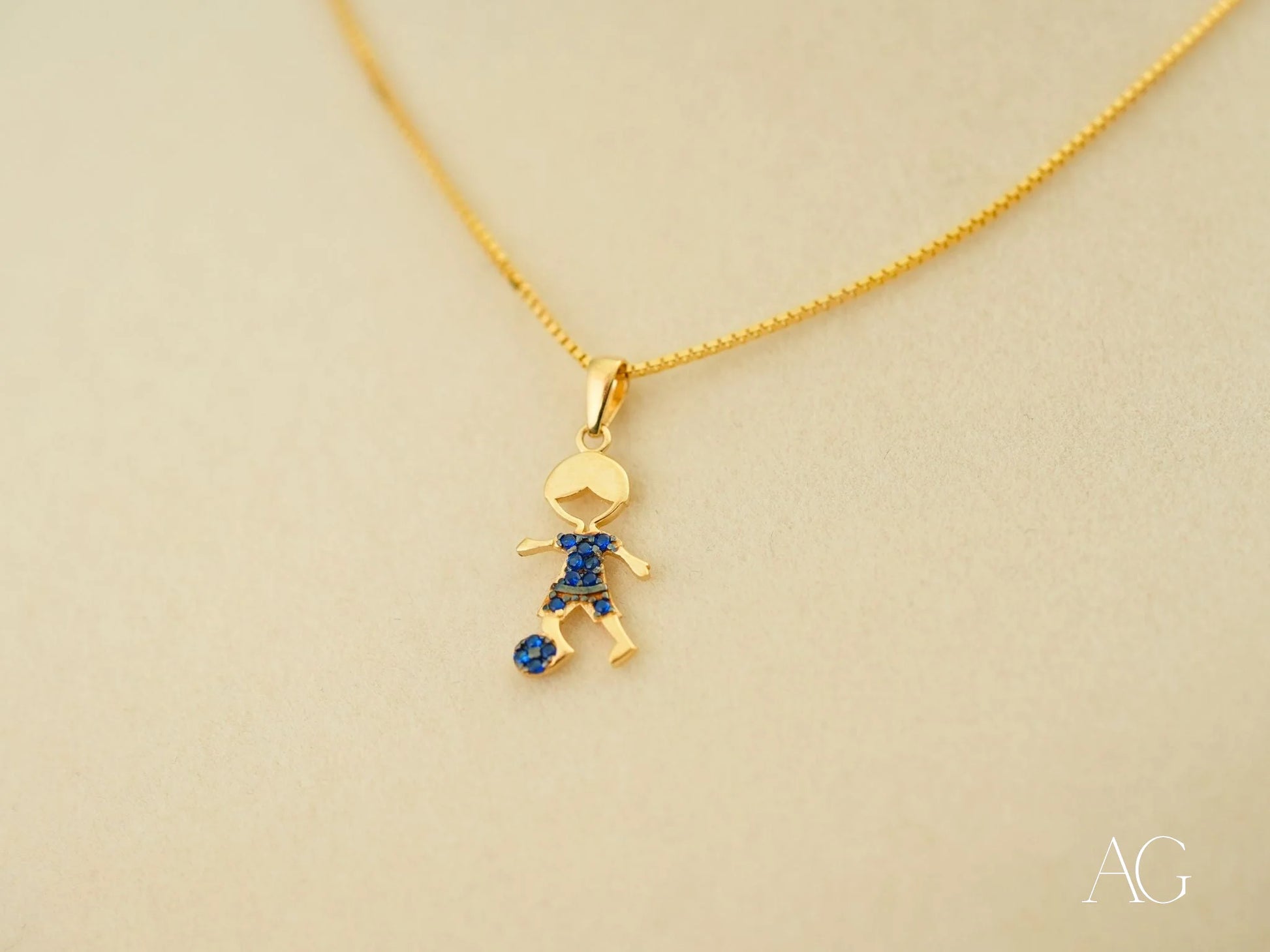 Gold pendant necklace with boy charm and blue gemstones in 18k yellow gold