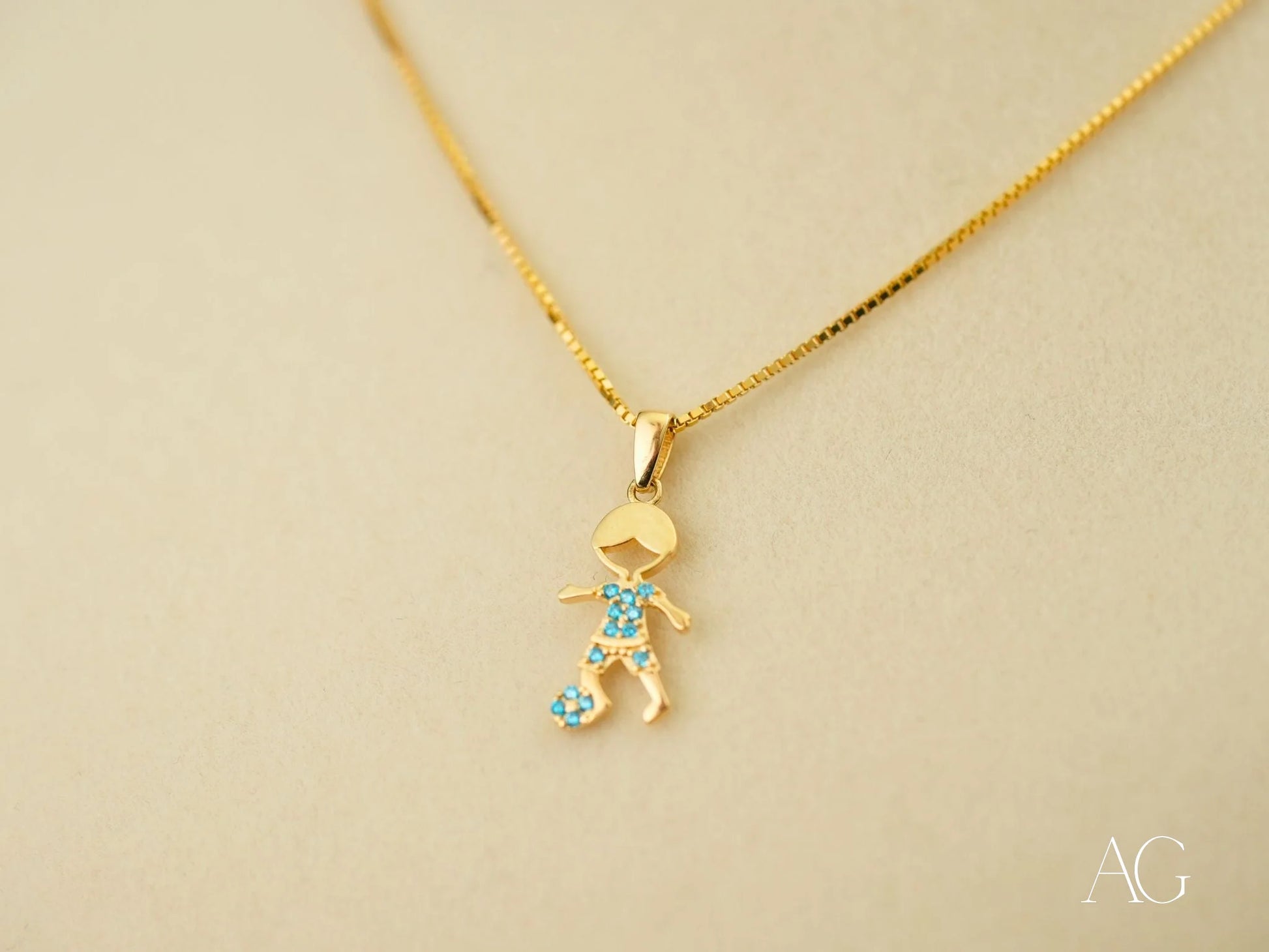 Gold pendant necklace in 18k yellow gold with stick figure charm and blue gemstones