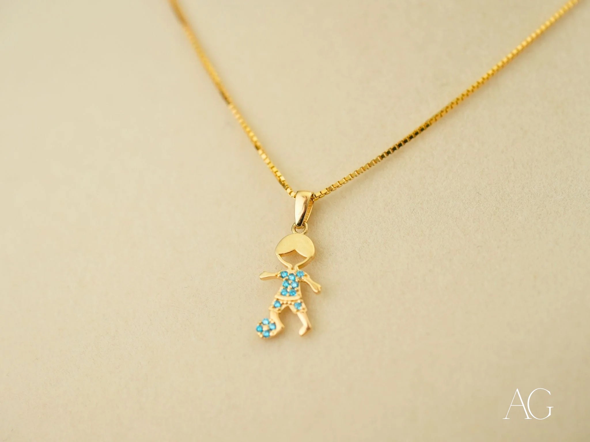 Gold pendant necklace in 18k yellow gold with stick figure charm and blue gemstones