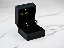 Gold ball earrings in a black jewelry box showcasing 18k gold ball drop design