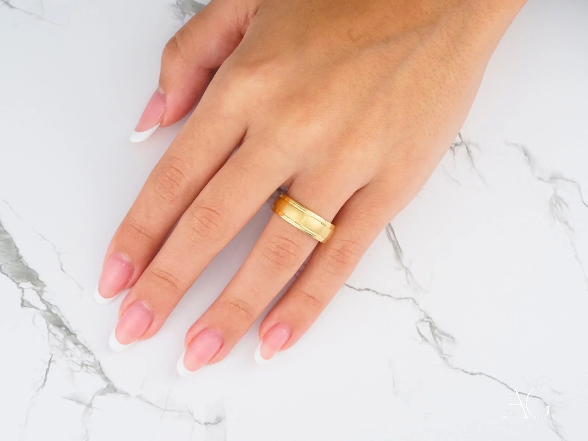 Gold ring featuring Golden Fortress Wedding Band on a manicured finger with 14k gold