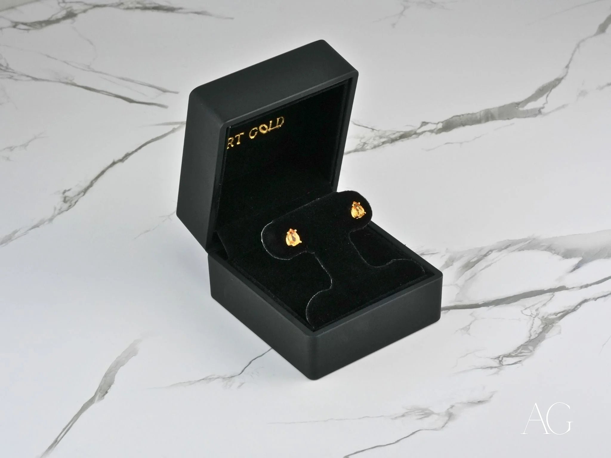 Gold citrine earrings in a black jewelry box featuring 18k gold and pear-cut citrine gemstones