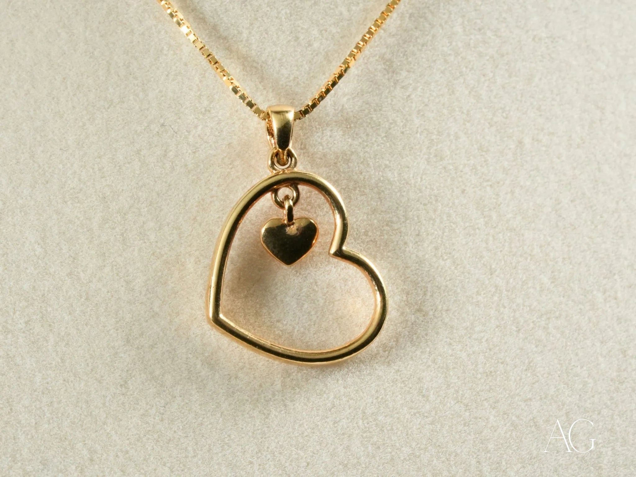 Gold heart pendant showcasing a smaller dangling heart charm on a delicate chain