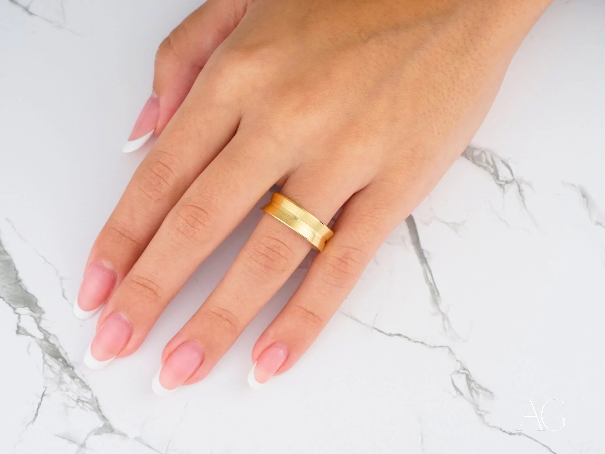 Gold wedding band on manicured finger showcasing 14k gold comfort fit design