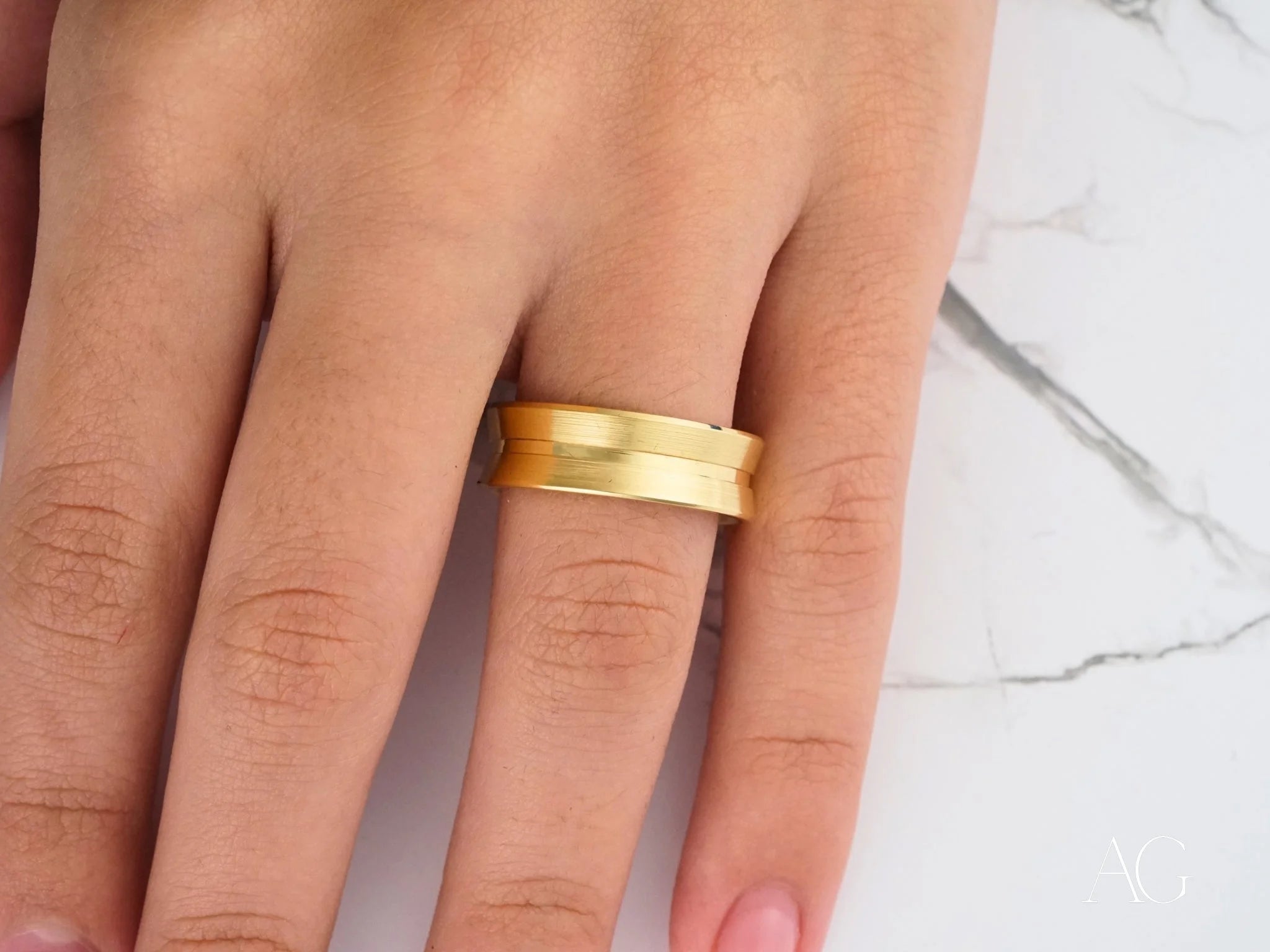 Gold wedding band on a finger showcasing the Comfort Fit design in 14k gold