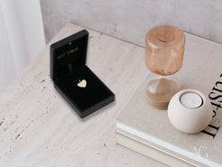 Black jewelry box with gold heart emblem and 18k gold Golden Love Pendant inside