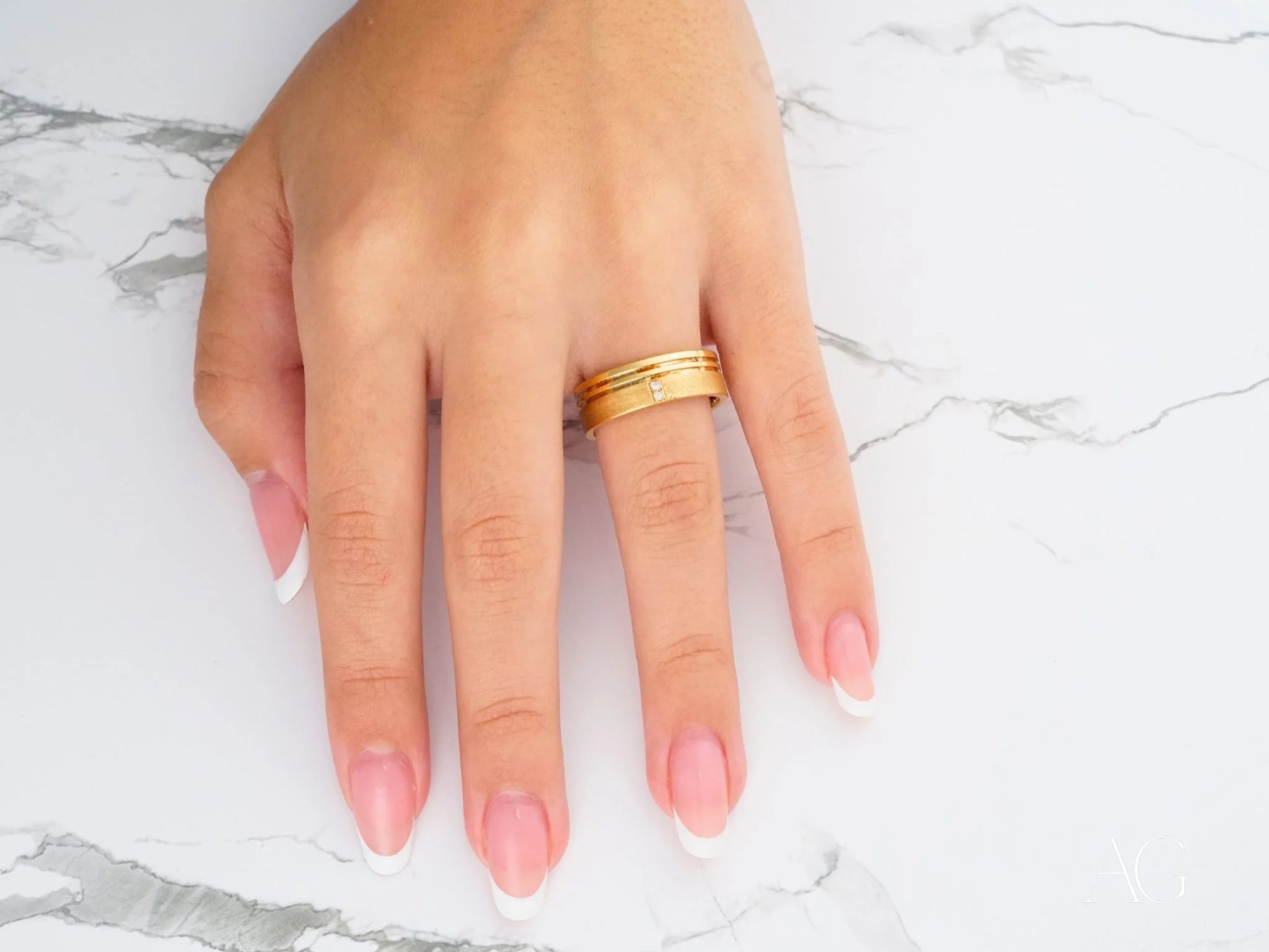 Gold ring with diamond accent on pink manicured nails for Golden Meridian Wedding Band