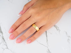 14k Gold Imperial Facet Wedding Band on a person’s ring finger in classic fit