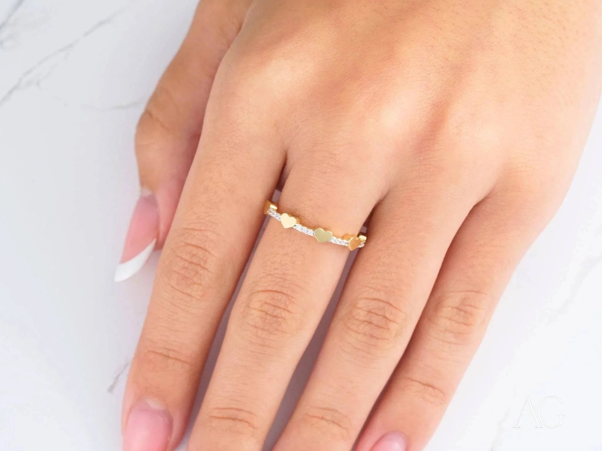 Delicate 18k yellow gold braided ring worn on a finger, showcasing elegant design