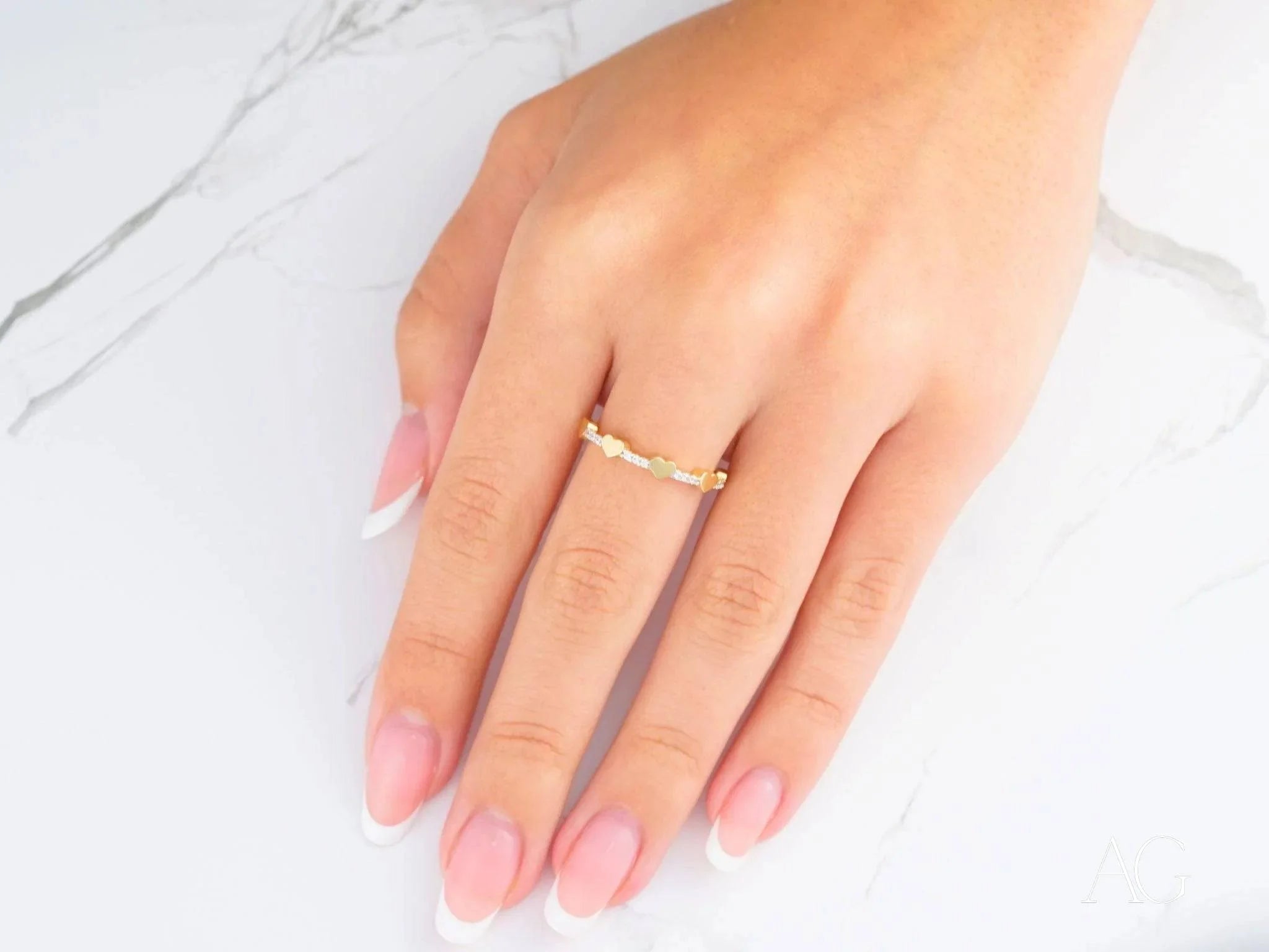 Gold ring with a diamond on manicured nails showcasing 18k yellow gold elegance