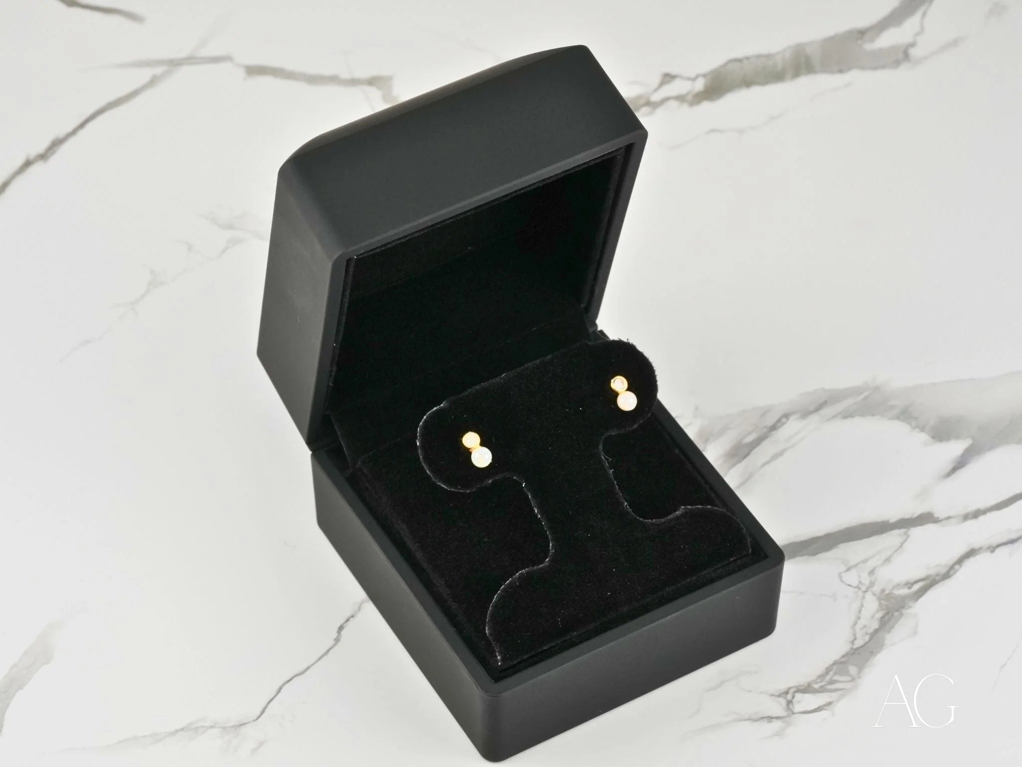 Gold stud earrings in a black jewelry box for Lustrous Harmony 18K Gold Pearl Drop Earrings