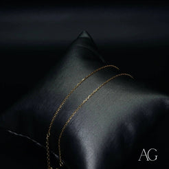 Delicate 18k gold anklet elegantly draped on a dark cushion for luxurious display