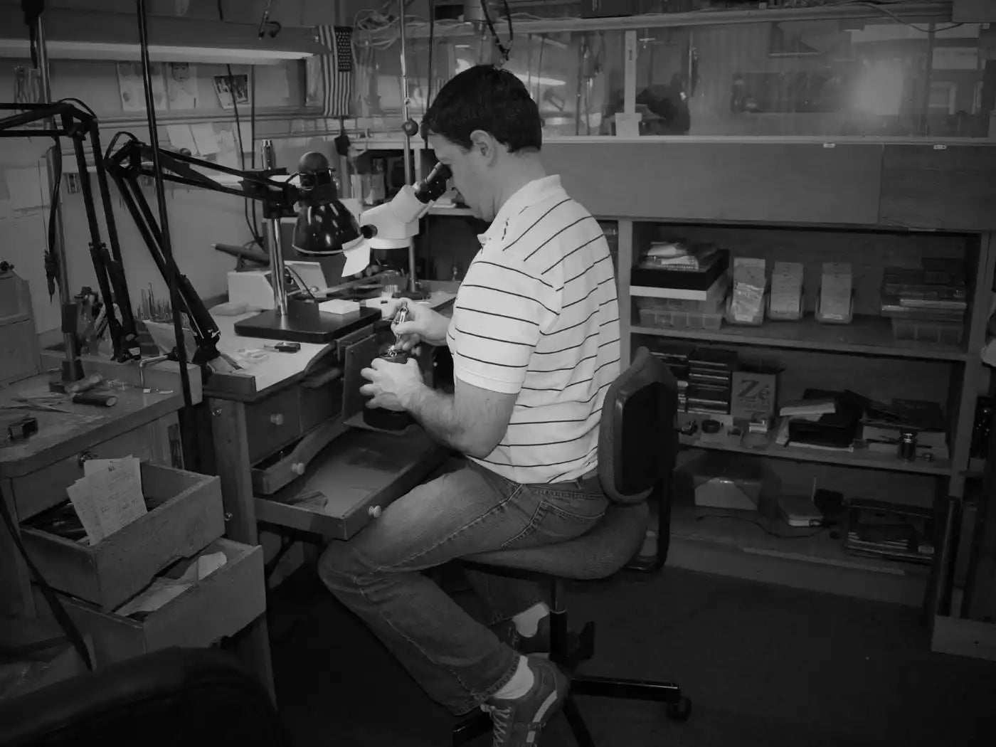 Someone working at a microscope station while seated on a stool.