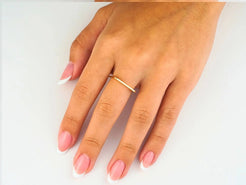 Gold ring with square shape 18k gold design on a finger with pink manicured nails