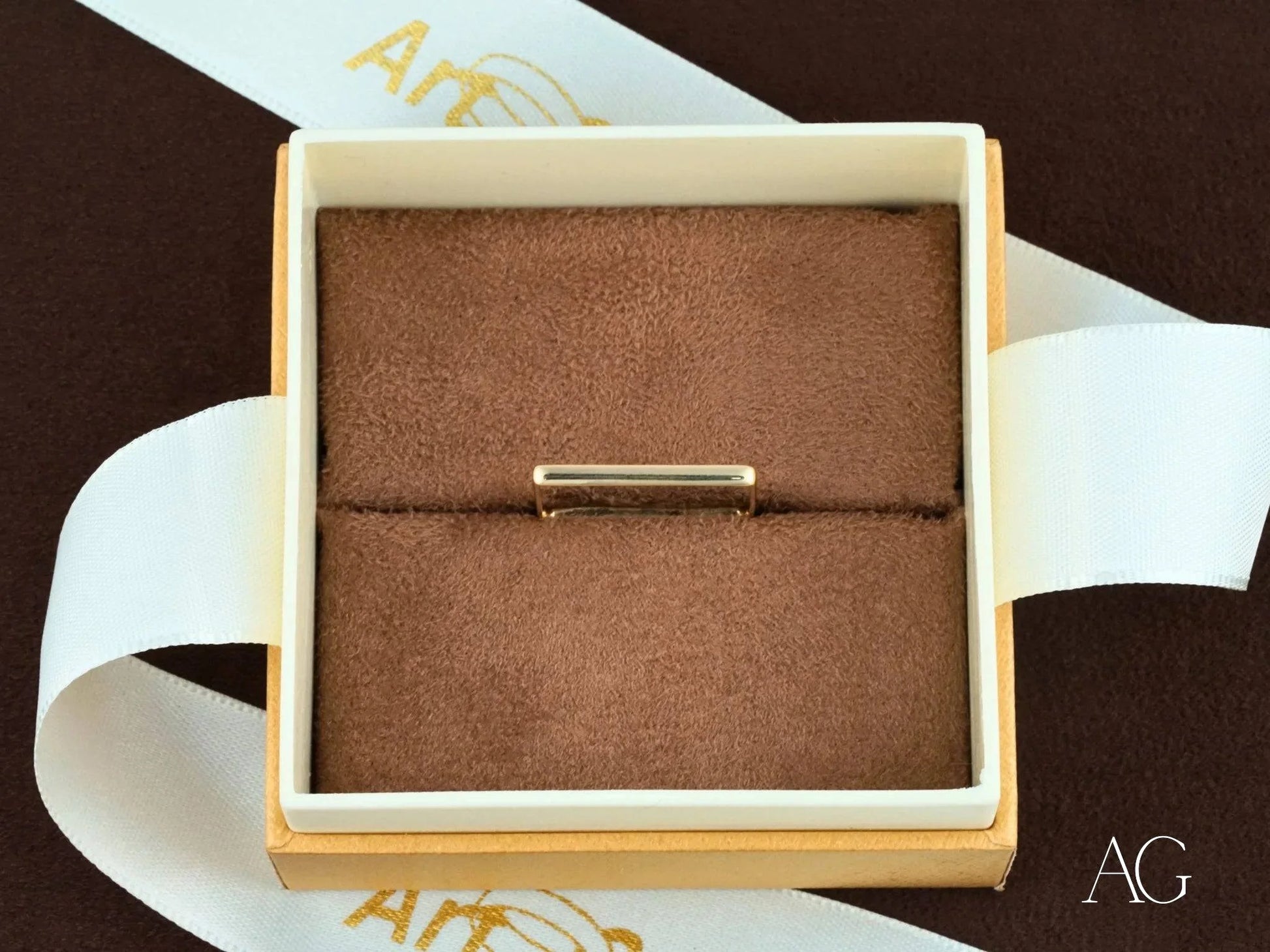 Delicate gold bracelet in a square jewelry box with brown velvet, showcasing square shape 18k elegance