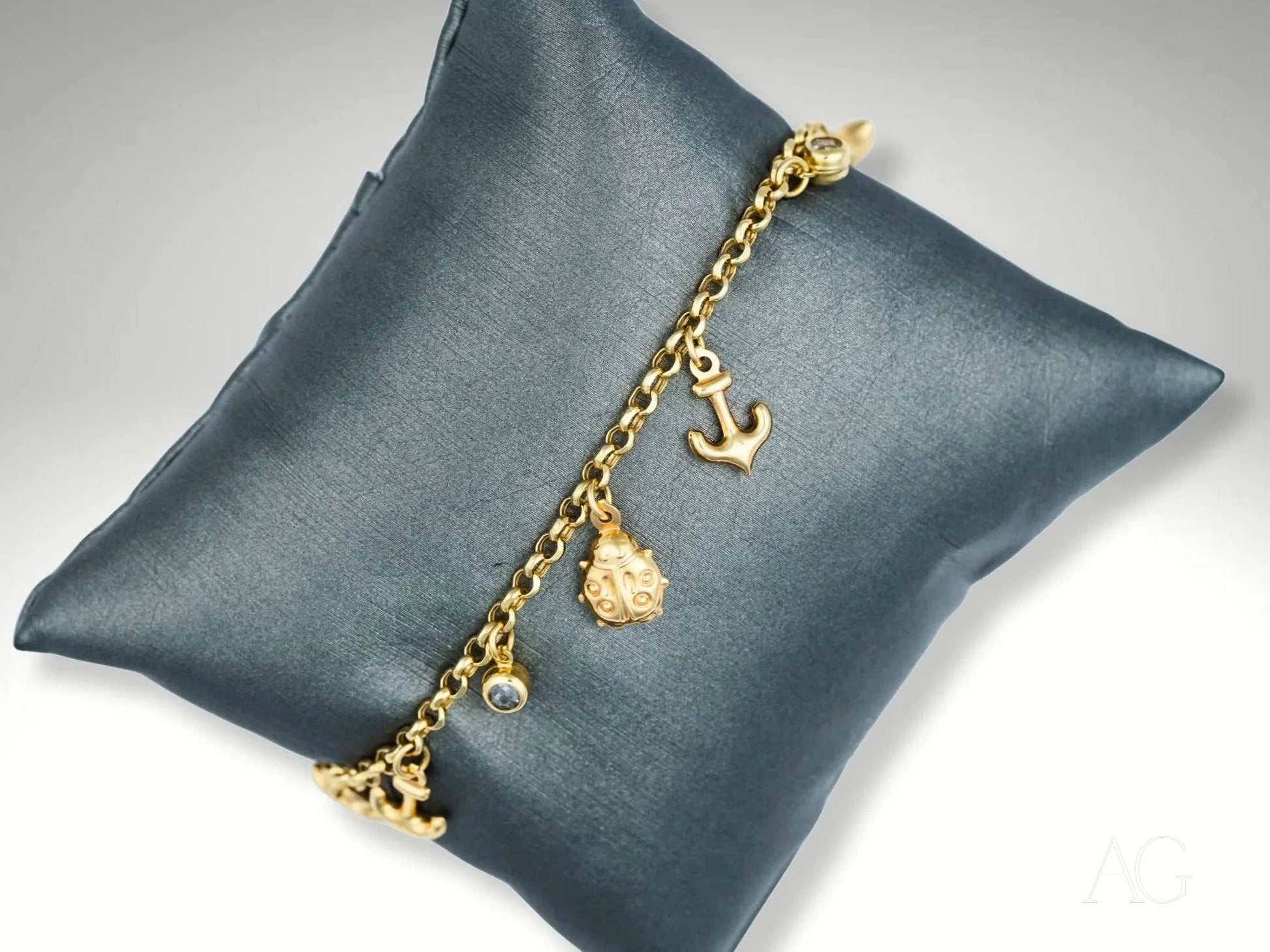 18k gold charm bracelet with nautical elegance and sea-inspired pendants on gray cushion