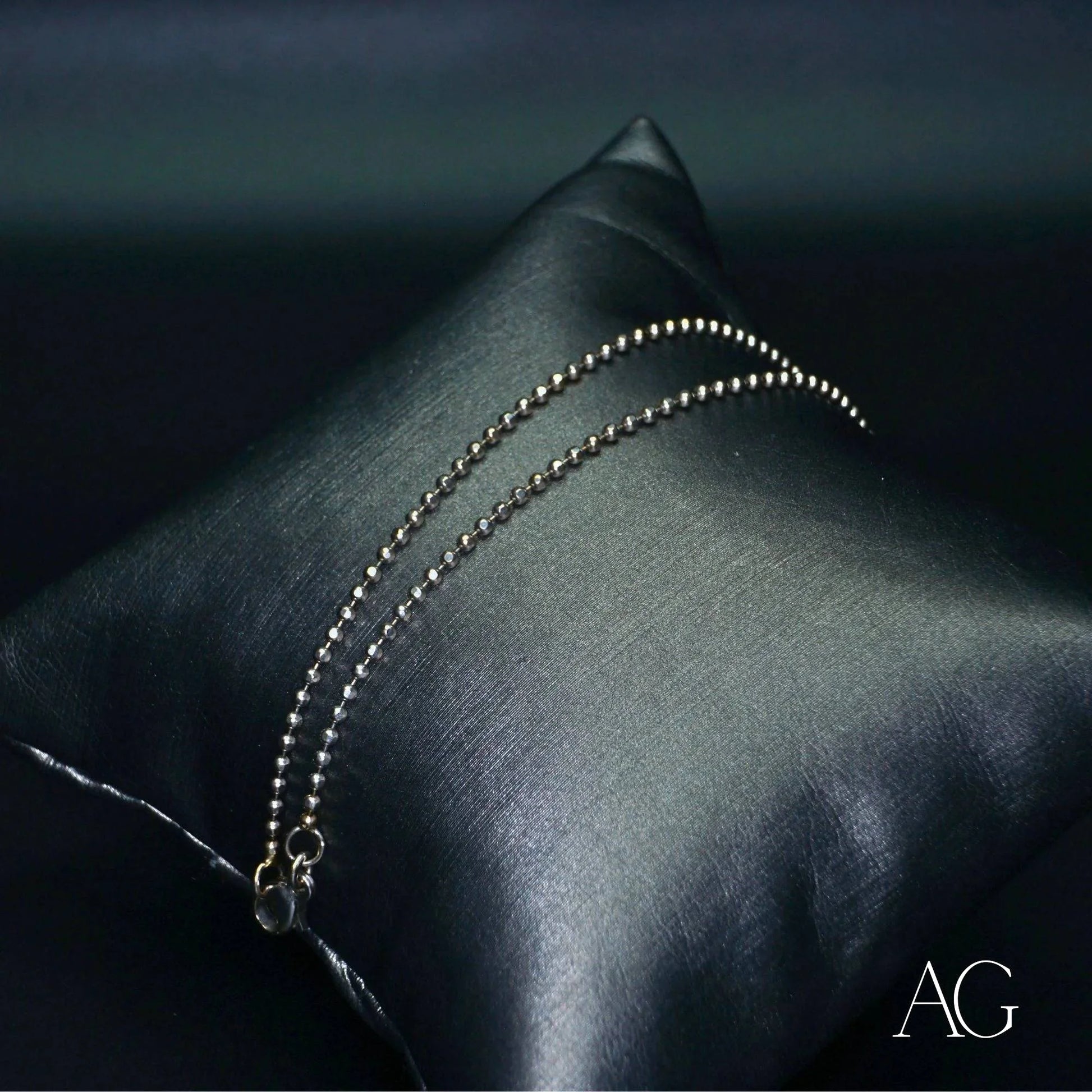 Elegant 18k white gold anklet on a dark satin pillow with a delicate chain design