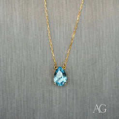 Gold necklace featuring a teardrop-shaped blue topaz pendant and 18 carat gold chain