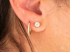 Pierced ear featuring elegant 18k yellow gold mini hoops earrings