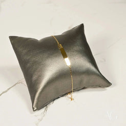 Metallic silver cushion showcasing a Regal Elegance 18k solid gold bracelet with crown motif