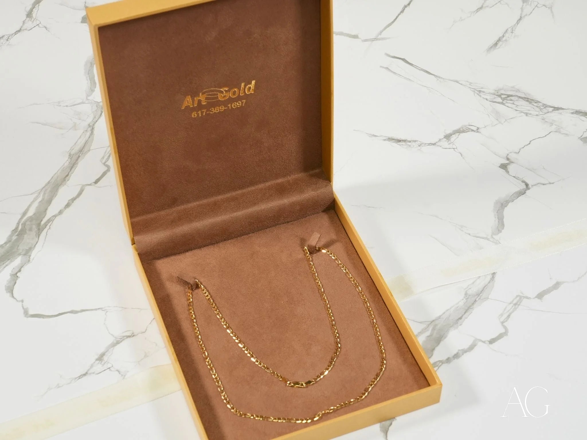 Gold necklace in a presentation box featuring Regal Prestige 18K Yellow Gold Figaro Chain