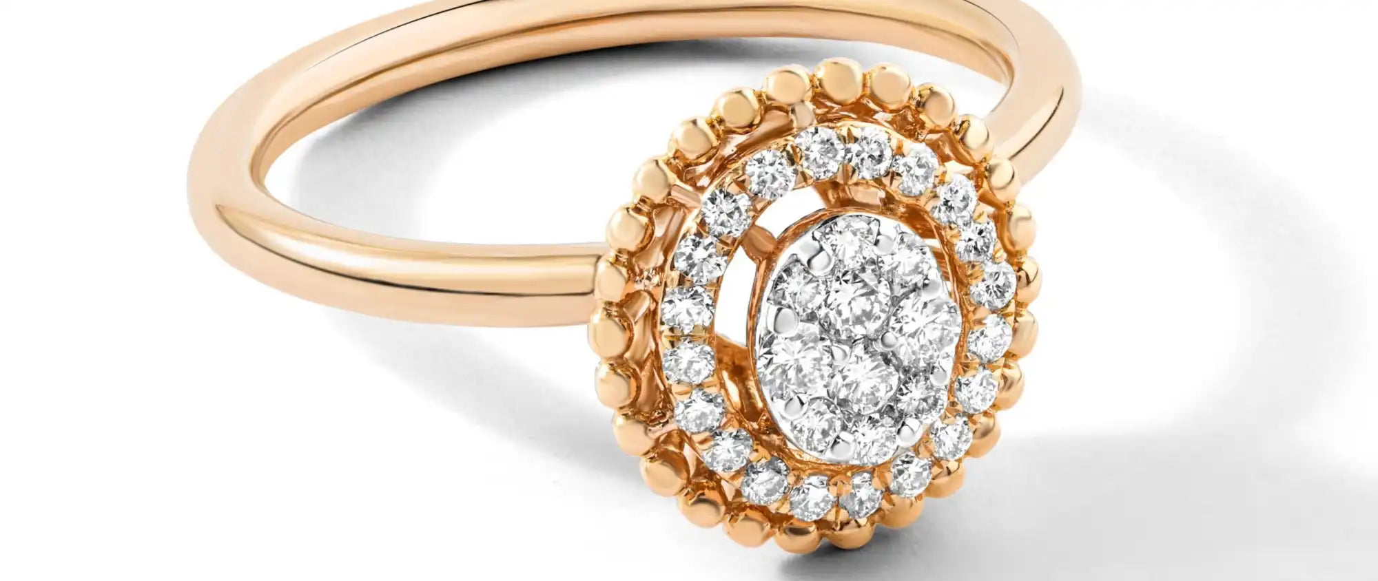 Rose gold engagement ring featuring an oval diamond center stone surrounded by a double halo of smaller diamonds.