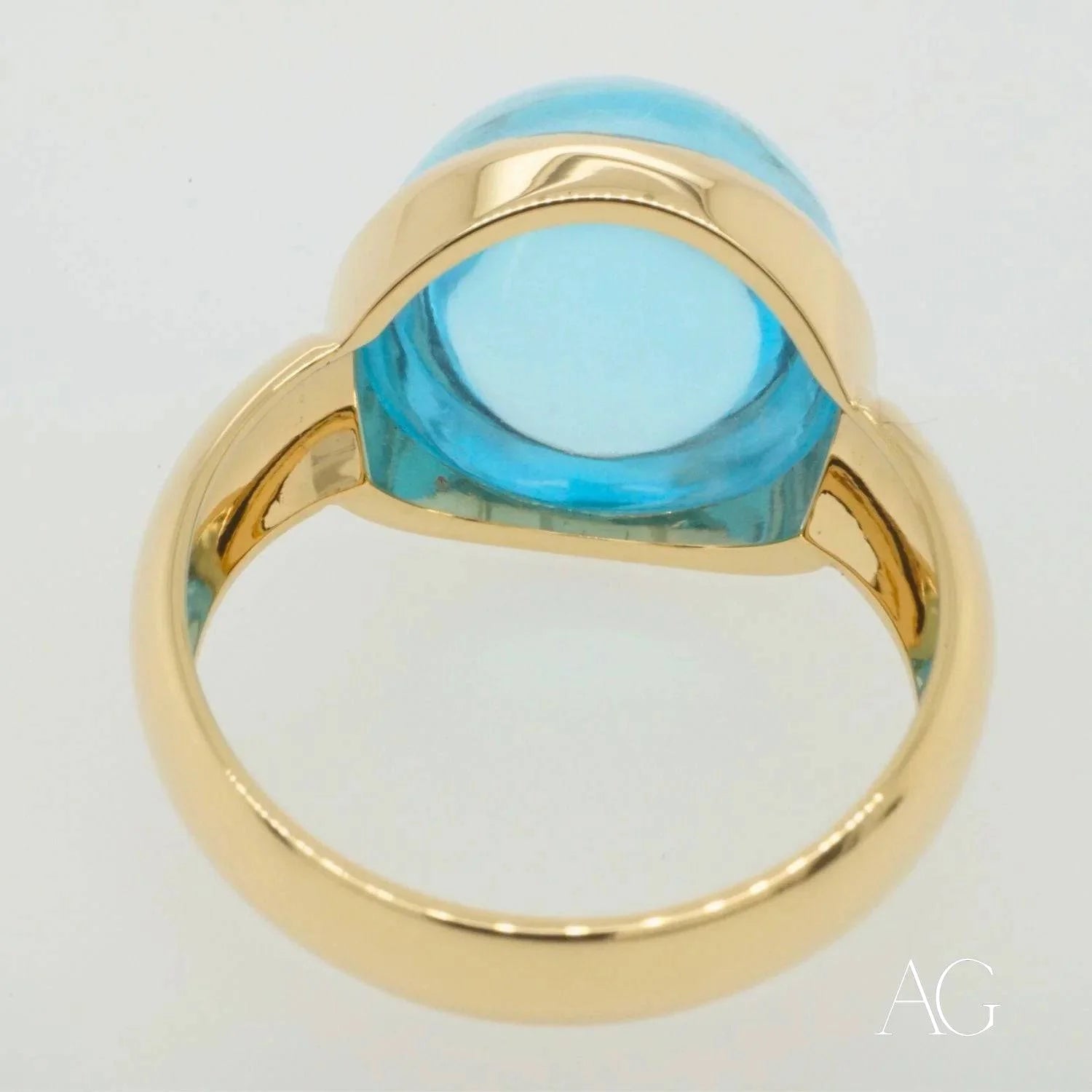 Gold ring featuring a vibrant cabochon blue topaz in an elegant oval setting