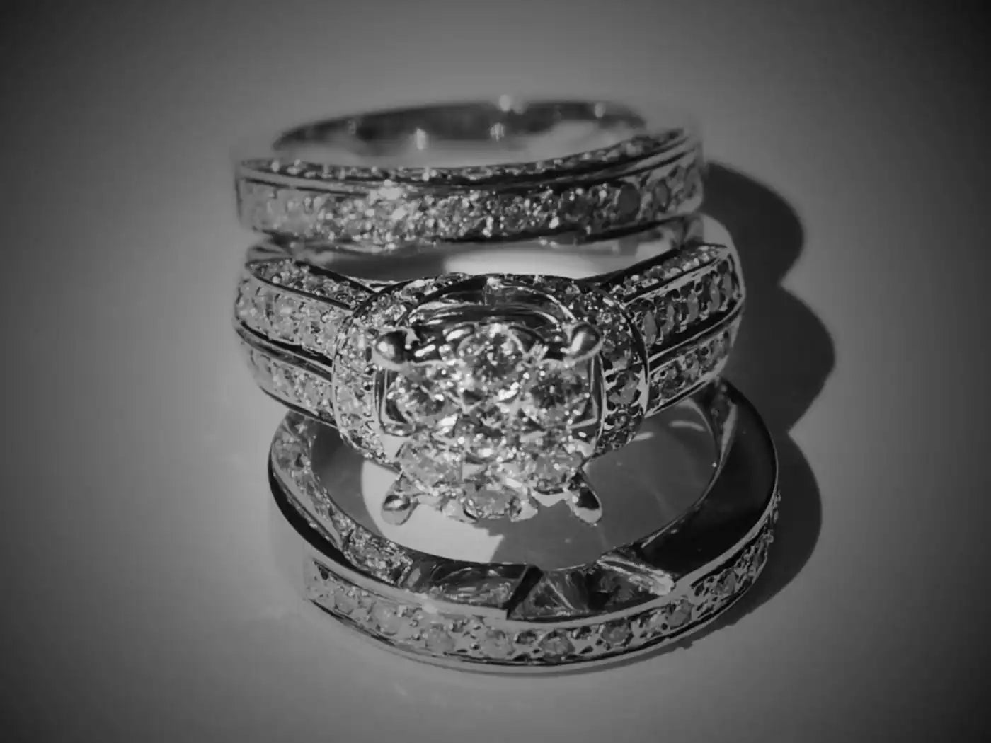 Three diamond-encrusted wedding rings stacked together in black and white.