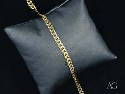 Gold Cuban link bracelet in 18k solid gold on a dark cushion for timeless elegance