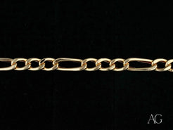 Gold-colored figaro bracelet with alternating long and short links in 18k gold