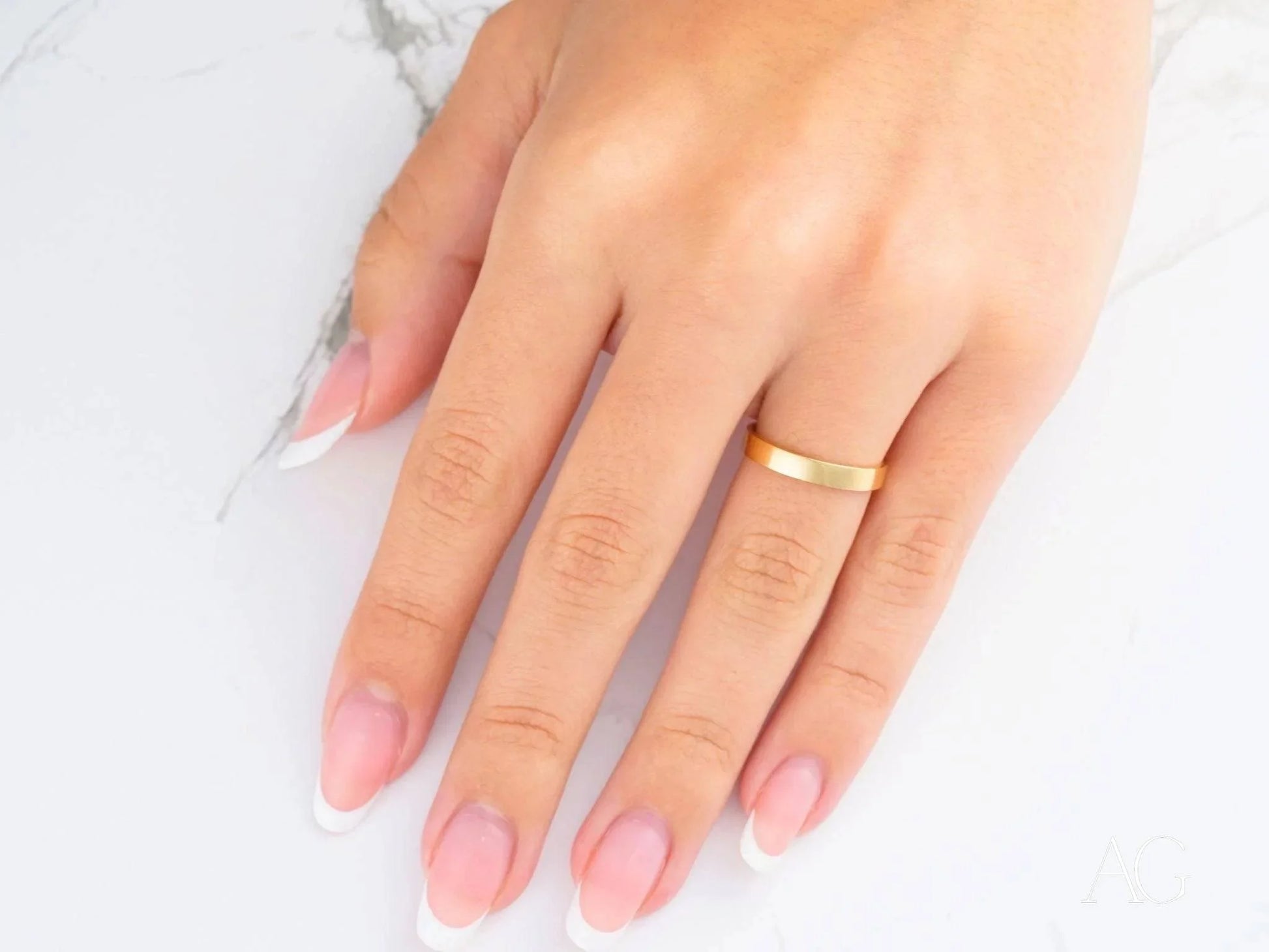 Hand wearing an 18k yellow gold band on the ring finger for timeless elegance