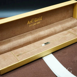 Gold-colored jewelry box with Art Gold branding holding a solid gold necklace